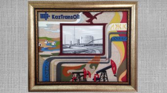 КазТрансОйлДекоративное панно посвящено КазТрансОйл - крупнейшей нефтепроводной компании Республики Казахстан, оказывающей услуги по транспортировке нефти на внутренний рынок и на экспорт.В центре картины расположено изображение резервуаров для хранения нефти, выполненное в технике монохромной росписи. КазТрансОйл, являющийся национальным оператором по магистральному нефтепроводу, направляет все свои усилия на повышение надежности существующих и строительство новых мощностей по транспортировке и перевалке нефти.Тематика нефтепровода продолжается в символическом изображении труб, которые выходят за пределы картинной плоскости. Это говорит о дальнейшем развитии компании, которая осваивает все новые и новые регионы. Станки-качалки в нижней части картины являются важнейшим элементом нефтегазового оборудования, отражают один из аспектов деятельности компании и символизируют процветание и благоденствие. Декоративное изображение языков пламени – это символ тепла, света и добра, которые приносят в повседневную жизнь нефть и газ, ведь без этих важнейших источников невозможно представить себе современную жизнь.Степной пейзаж с юртами и небольшой речкой – образ казахстанской земли, которая имеет такие большие запасы природных богатств и недр. Но главное богатство нашей страны – это великий народ, который гордится не только своими творцами и поэтами, художниками и композиторами. Казахстанский народ выдвигает вперед своих лучших сынов и дочерей, которые являются умелыми и мудрыми руководителями, ведущими за собой людей. Одному из таких руководителей, чьи инициалы расположены на картине, и посвящена данная работа.Логотип компании КазТрансОйл завершает композицию панно. Беркут, расправляющий крылья, словно продолжение логотипа, символизирует стремление к свободе, высоту помыслов, силу и быстроту, величие и проницательность. Компания КазТрансОйл, как гордая птица, еще только расправляет свои крылья мечты, набирая высоту, имея грандиозные замыслы и проекты. Впереди светлая и ясная дорога, полная свершений и побед, впереди прекрасное будущее.